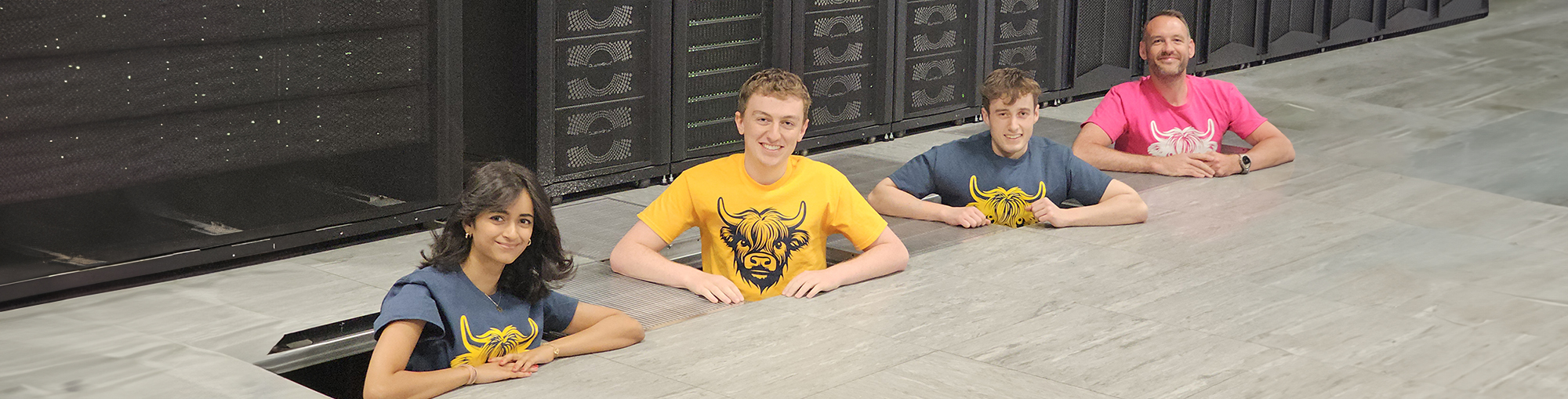 Left to right: Vaidehi, Alistair, James and EPCC Director of HPC Systems Paul Clark demonstrate a raised floor in the ACF. ARCHER2, seen in the background, is hosted in this computer room.