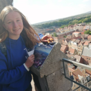 Libby standing on the balcony of a historic building overlooking roof tops of a town.