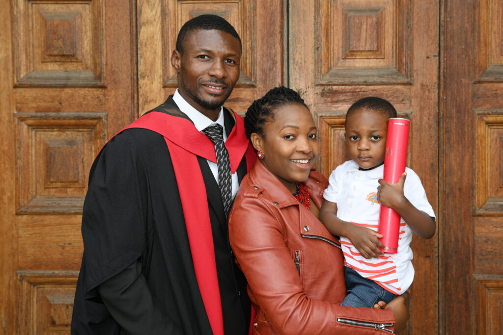A graduate in front of the doors of the McEwan Hall