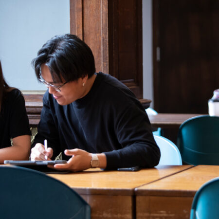 Photo of student and tutor chatting over work on table