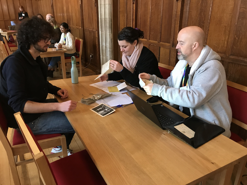 Photograph of Eden, Fiona and Paul sitting around a table examining artefacts at the Digital Collection Day.
