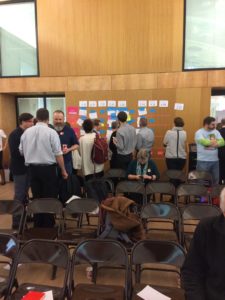 A crowd of people review notices on a wall