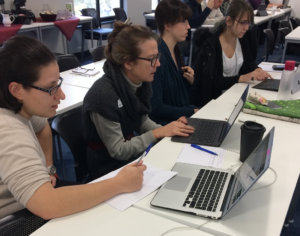 People work in pairs at laptop computers